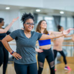 a diverse group dance along to the music together in an exercise dance class.