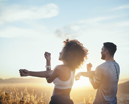 shot of a young couple stretching while out for a workout on a mountain road